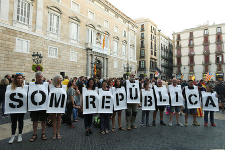 People hold placards that read, "We are republic", as they stage a sit-in during an occupation of the Sant Jaume square, as a part of events planned to mark the first anniversary of the banned independence referendum held in the region on October 1, 2017, in front of the Catalan regional government headquarters in Barcelona, Spain, September 29, 2018. REUTERS/Jon Nazca