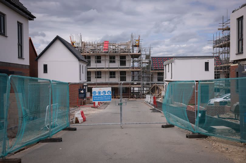 Unfinished homes on new build housing estate with fencing in front