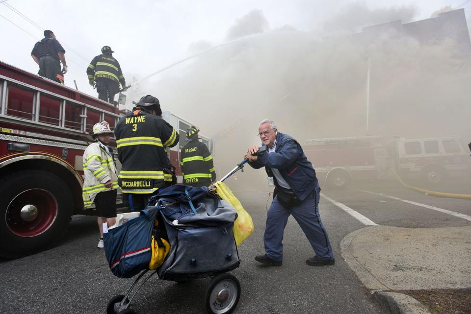 A mailman wheels his cart through the scene of a 6-alarm fire at 112 Gregory Ave. in Passaic in 2017.