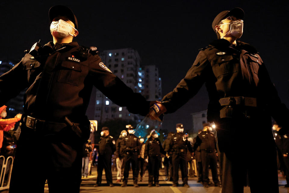 Police officers stand guard as people protest in Beijing.