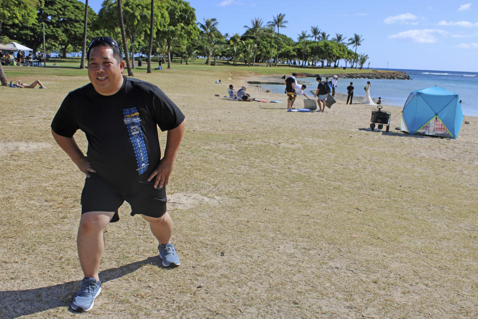 CORRECTS SPELLING OF LAST NAME TO YUKUTAKE- NOT YAKUTAKE- Todd Yukutake, a director of the Hawaii Firearms Coalition, stretches before exercising in a beach park in Honolulu on Thursday, June 29, 2023. The coalition is suing to block a new Hawaii law that prohibits carrying guns in sensitive locations including parks and beaches. Beginning Saturday, JUly 1, 2023, a new law prohibits carrying a firearm on the sand — and in other places, including banks, bars and restaurants that serve alcohol. (AP Photo/Jennifer Sinco Kelleher)