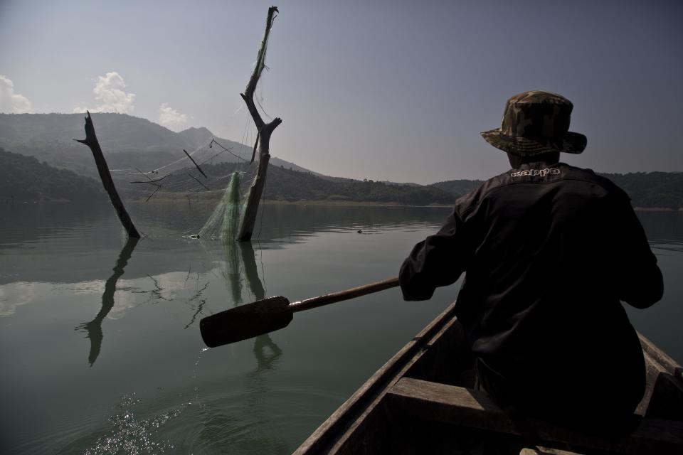 In this Saturday, Nov. 10, 2018, photo, a villager rows a boat past an abandoned fishing net at the Doyang reservoir in Wokha district, in the northeastern Indian state of Nagaland. The people in the area transformed from being hunters—killing up to 15,000 migratory Amur Falcons a day in 2012—to conservators - a feat that locals regard as one of the biggest conservation success stories in South Asia. (AP Photo/Anupam Nath)