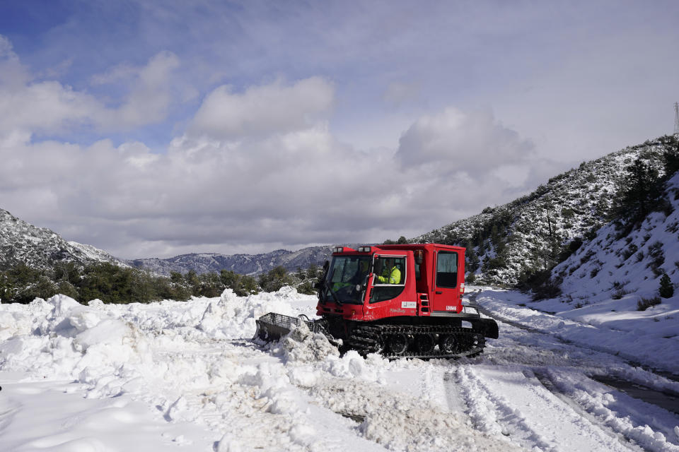 A worker plows snow along State Route 138 near Hesperia, Calif., Wednesday, March 1, 2023. Emergency crews are scrambling to shuttle food and medicine to residents of California mountain communities stranded by back-to-back winter storms. (AP Photo/Jae C. Hong)