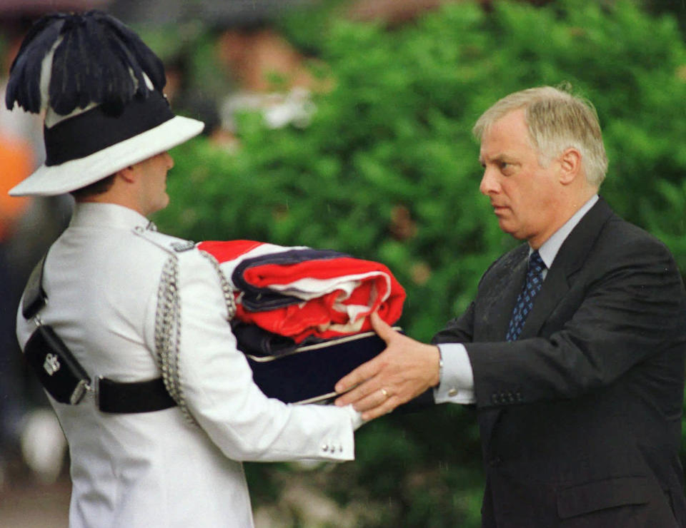 FILE - Then Gov. Chris Patten, right, receives a folded British flag after its lowering at Government House in Hong Kong on June 30, 1997 as the British colony reverts to Chinese rule at midnight. (AP Photo/Eric Draper, File)