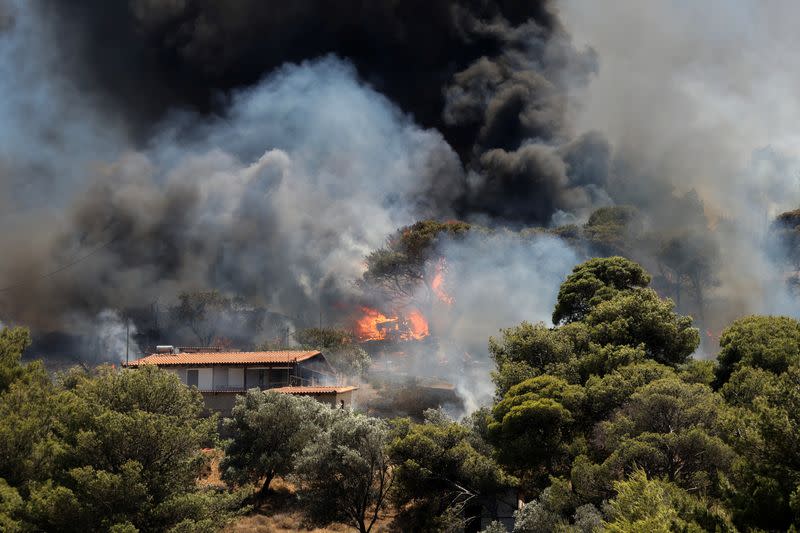 Las llamas se elevan junto a una casa mientras arde un incendio forestal en Keratea, cerca de Atenas, Grecia