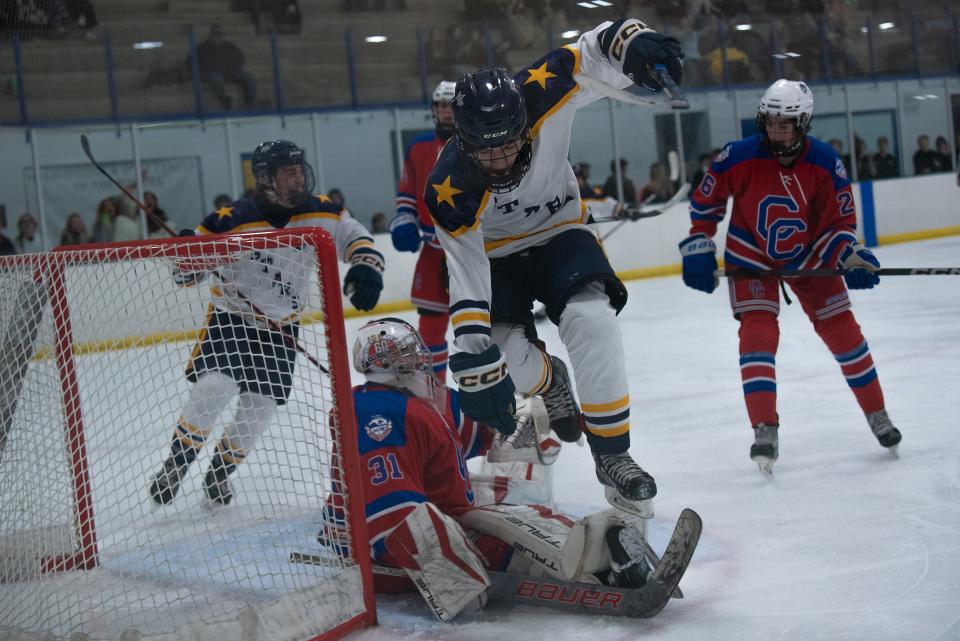 A Poudre School District ice hockey player jumps over the Cherry Creek goalie during a game against Cherry Creek on Friday, January 26, 2024, at NoCo Ice Center in Windsor, Colo.