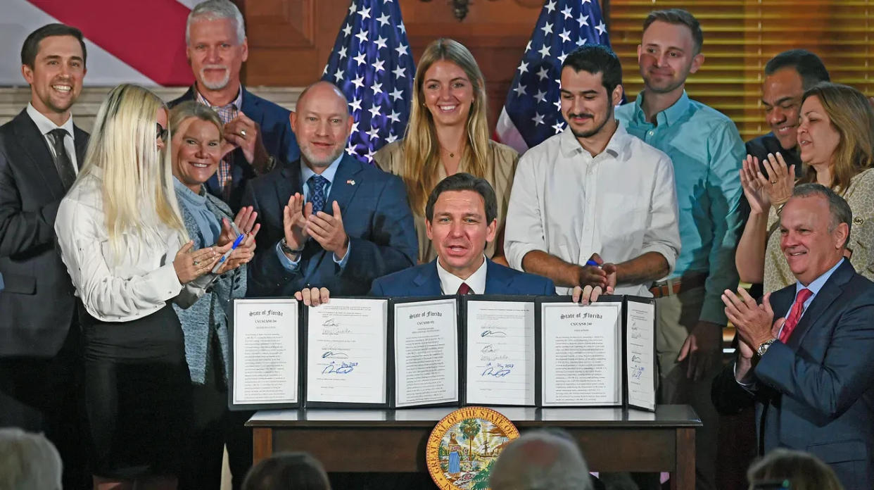 Gov. Ron DeSantis signs three bills May 15 at New College, in Sarasota. One bill bans state funding for diversity, equity and inclusion programs at Florida's public universities. DeSantis is surrounded by supporters, including New College Interim President Richard Corcoran, right.