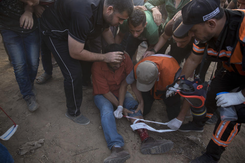 Palestinian medics treat a wounded protester was shot by Israeli troops at the Gaza Strip's border with Israel, Friday, Oct. 19, 2018. (AP Photo/Khalil Hamra)