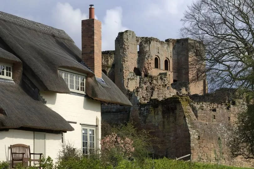 A thatched house with Kenilworth Castle in the background