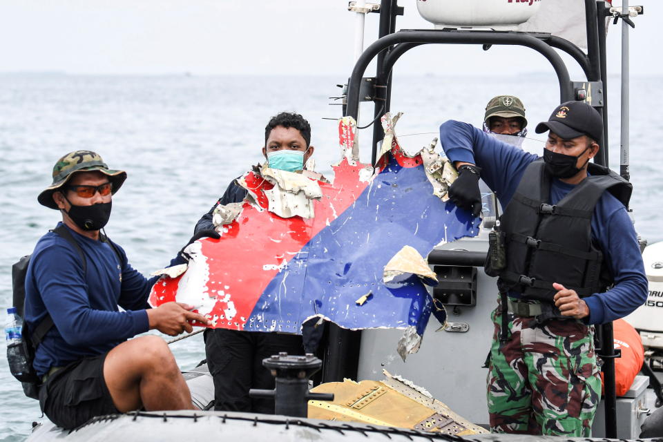 Indonesian Navy personnel carry debris believed to be from the Sriwijaya Air SJ-182 plane, which crashed into the sea, off the Jakarta coast.