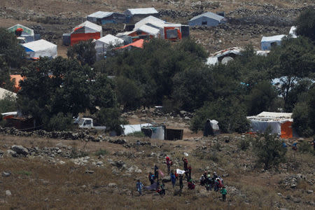 People wave white cloths next to the refugee tents erected near the border fence between Israel and Syria from its Syrian side as it is seen from the Israeli-occupied Golan Heights near the Israeli Syrian border July 17, 2018. REUTERS/Ronen Zvulun