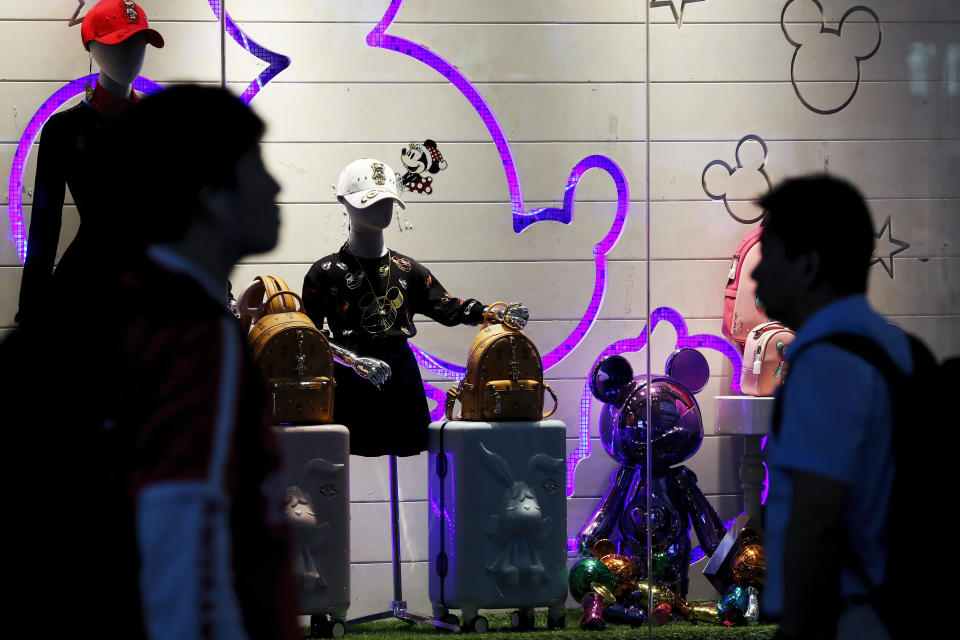 Passengers walk by merchandise on display at the Shanghai Disney flagship store at Hongqiao Railway Station in Shanghai, China, Monday, Oct. 14, 2019. China's trade with the United States fell by double digits again in September amid a tariff war that threatens to tip the global economy into recession. (AP Photo/Andy Wong)