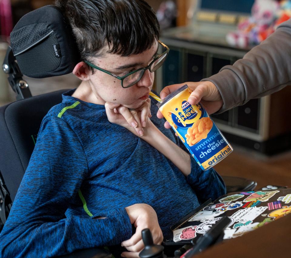 Alexander Davis, 15, gets a hand with a beverage on Sunday, Jan 21, 2024, at the family’s Tipton home. A recent Family and Social Services Administration decision is slated to eliminate financial reimbursement for family members who care for severely disabled and medically complex children.