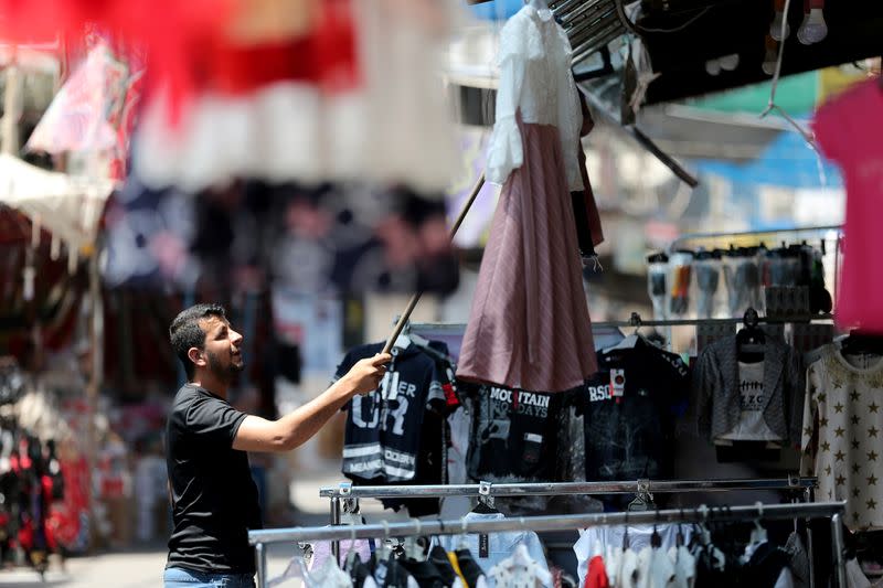 A man hangs a dress at a shop as Palestinians prepare for the upcoming holiday of Eid al-Fitr marking the end of Ramadan, amid concerns about the spread of the coronavirus disease
