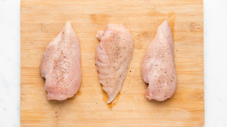 seasoned chicken breasts on chopping board