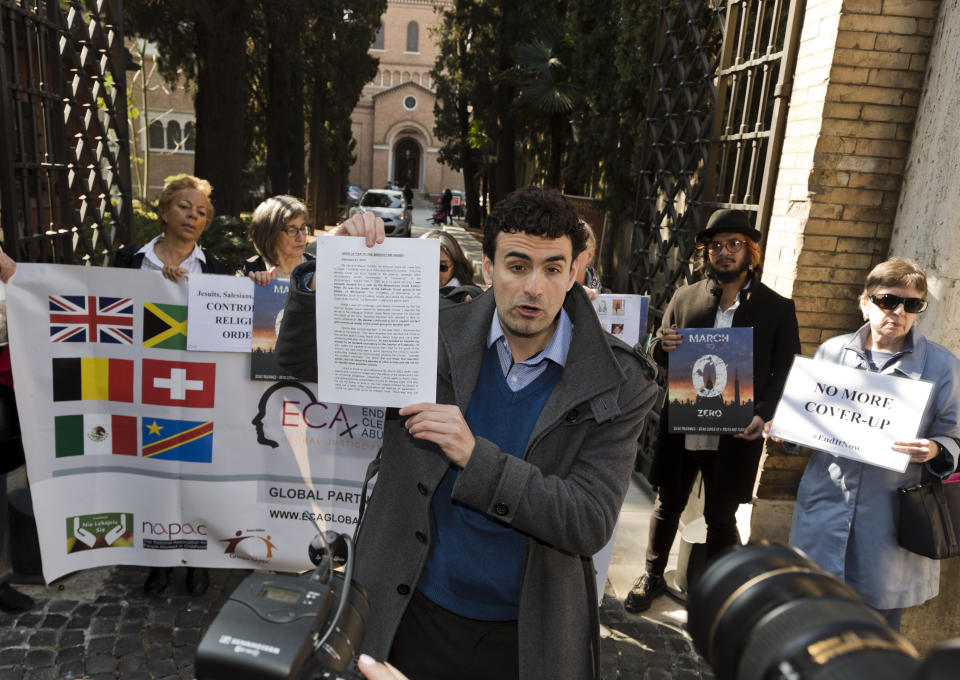 Child psychologist and founding member of the Ending Clergy Abuse (ECA) organization, Miguel Hurtado from Spain, center, shows an open letter to the Benedictine order before delivering it, outside the St. Anselm on the Aventine Benedictine complex in Rome on the second day of a summit called by Pope Francis at the Vatican on sex abuse in the Catholic Church, Friday, Feb. 22, 2019. Pope Francis has issued 21 proposals to stem the clergy sex abuse around the world, calling for specific protocols to handle accusations against bishops and for lay experts to be involved in abuse investigations. (AP Photo/Domenico Stinellis)