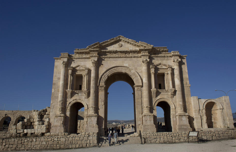 FILE - In this Nov. 13, 2015, file photo, tourists pass through the Arch of Hadrian, built during the Roman Empire, and the South Gate of the well preserved Ancient Roman city of Gerasa, in the city of Jerash, Jordan. Jordanian officials say an attacker has stabbed a number of tourists and their tour guide at a popular archaeological site in northern Jordan. The wounded were taken to a hospital and the attacker was arrested. (AP Photo/Nasser Nasser, FIle)