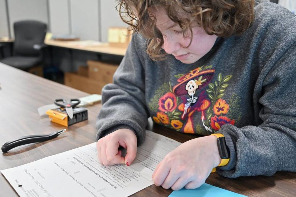 Student assistant Carmen Nehmer uses archival tape to repair a torn water rights document so it can be digitized with an automated document feeder.