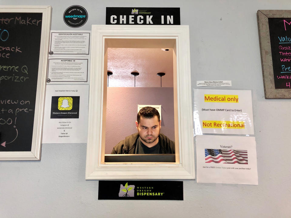 ADVANCE FOR PUBLICATION ON TUESDAY, JUNE 11, AND THEREAFTER - In this April 8, 2019, photo, Roberto Gonzalez, the general manager of Western Oregon Dispensary in Sherwood, Ore., waits for customers. The dispensary is one of two medical-only marijuana dispensaries left in Oregon. An Associated Press analysis has found existing medical marijuana programs take a hit when states legalize cannabis for all adults. (AP Photo/Gillian Flaccus)