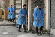 Iraqi volunteers spray disinfectant as a precaution against the coronavirus during a curfew, in a market in Baghdad, Iraq, Sunday, March 22, 2020. (AP Photo/Hadi Mizban)