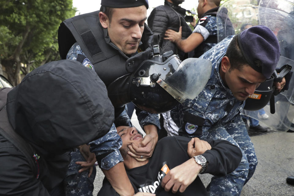 Riot police scuffle with anti-government protesters blocking a road in Beirut, Lebanon, Monday, Nov. 25, 2019. A key road has reopened in the Lebanese capital following clashes throughout the night between rival groups. (AP Photo/Hassan Ammar)