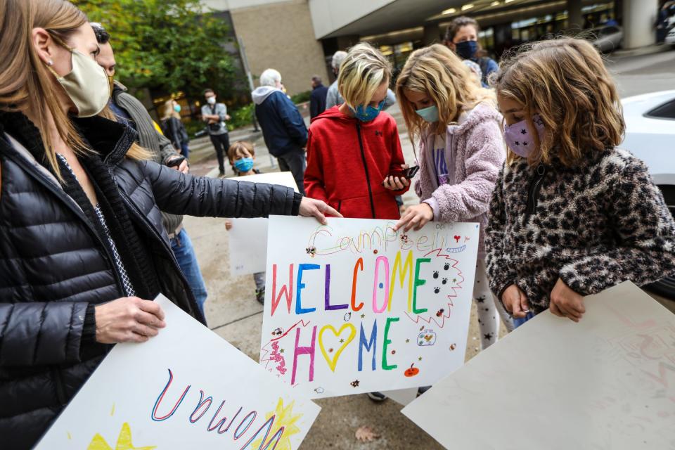 Grandchildren of Deanna Hair, Braylen, Campbell, and Landry Kaiser (left to right), grab the signs they made from their mother, Kristy Kaiser, as they wait for her to be discharged from the University of Michigan hospital in Ann Arbor, after being there for 196 days battling COVID-19 on Oct. 15, 2020.