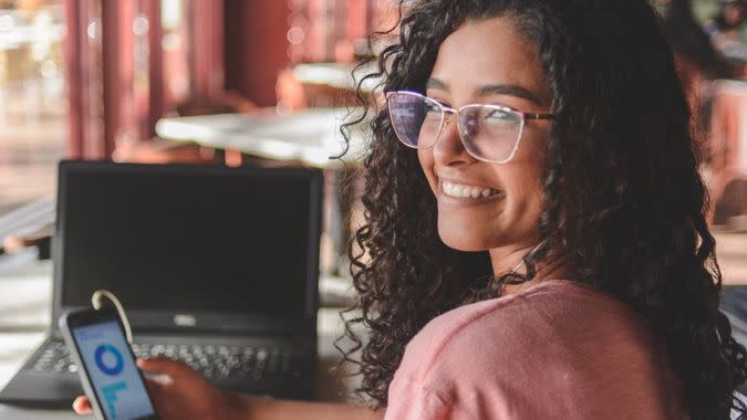 Portrait of young woman using financial app on smartphone.