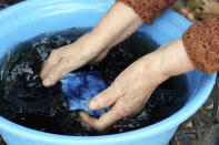 In this image from video, Yoshiko Ogura, 73, washs off an indigo-dyed handkerchief in front of her studio in Minamisoma, Fukushima Prefecture, northeastern Japan, on Feb. 20, 2021. After the Fukushima nuclear plant disaster a decade ago, nearby farmers weren't allowed to grow crops for two years because of radiation. After the restriction was lifted, two farmers in the town of Minamisoma found an unusual way to rebuild their lives and help their destroyed community. Kiyoko Mori and Ogura planted indigo and soon began dying fabric with dye produced from the plants. (AP Photo/Chisato Tanaka)