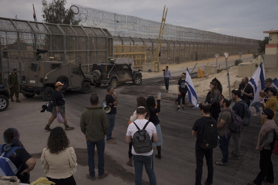 People stand in front of a gate at the Nitzana border crossing with Egypt in southern, Israel, Monday, Feb. 12, 2024, protesting against the humanitarian aid to enter Gaza until all the hostages are released. (AP Photo/Leo Correa)