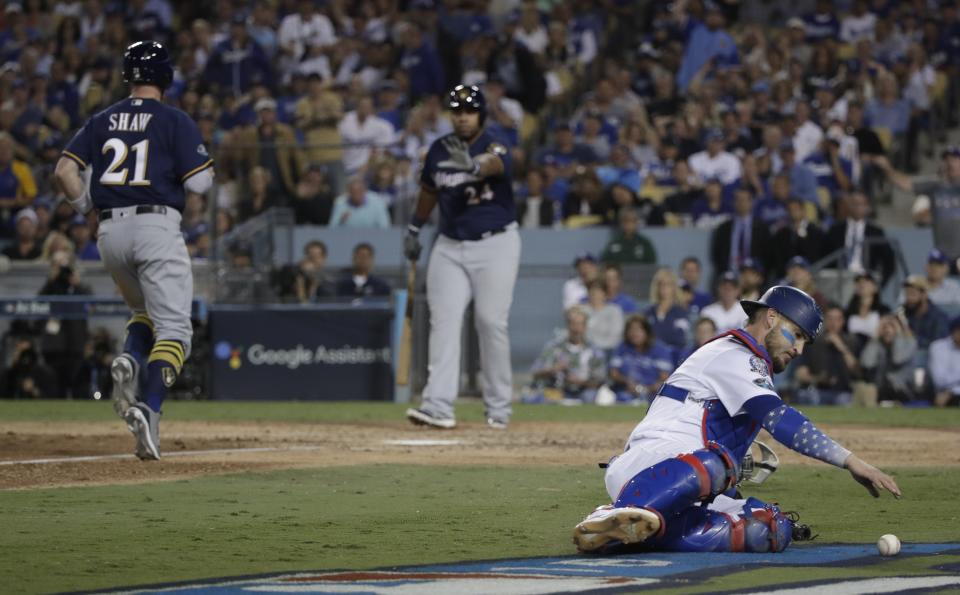 Los Angeles Dodgers catcher Yasmani Grandal goes after a wild pitch as Milwaukee Brewers' Travis Shaw scores during the sixth inning of Game 3 of the National League Championship Series baseball game Monday, Oct. 15, 2018, in Los Angeles. (AP Photo/Jae Hong)