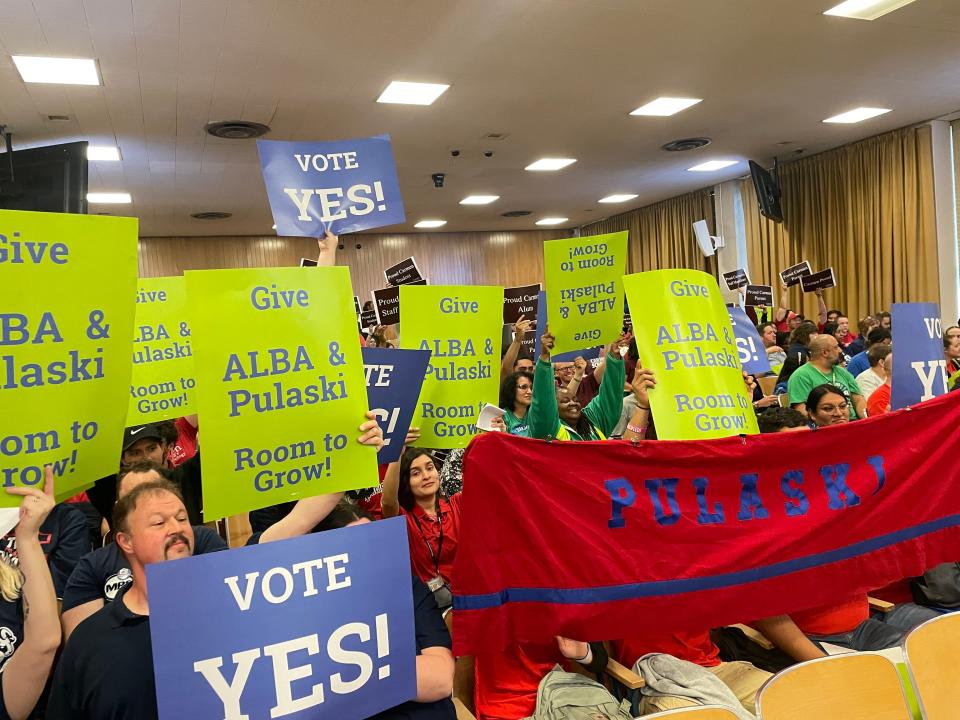At a Milwaukee School Board committee meeting May 21, dozens supporters of a resolution that would end leases for two Carmen Schools of Science and Technology campuses hold signs urging board members to "vote yes." Behind them, dozens of Carmen supporters hold signs expressing their own school pride.