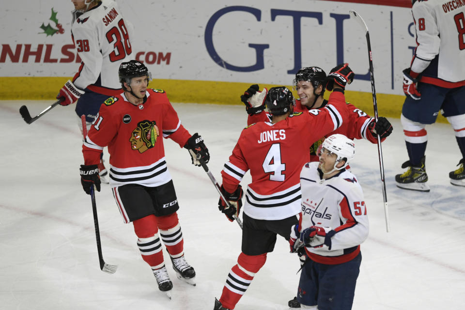 Chicago Blackhawks' Philipp Kurashev celebrates with teammate Seth Jones (4) while Anthony Beauvillier looks on after scoring a goal during the second period of an NHL hockey game against the Washington Capitals, Sunday, Dec. 10, 2023, in Chicago. (AP Photo/Paul Beaty)