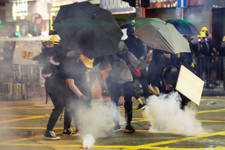 Anti-extradition bill protesters try to throw back tear gas canisters at the police during a protest in Causeway Bay, Hong Kong