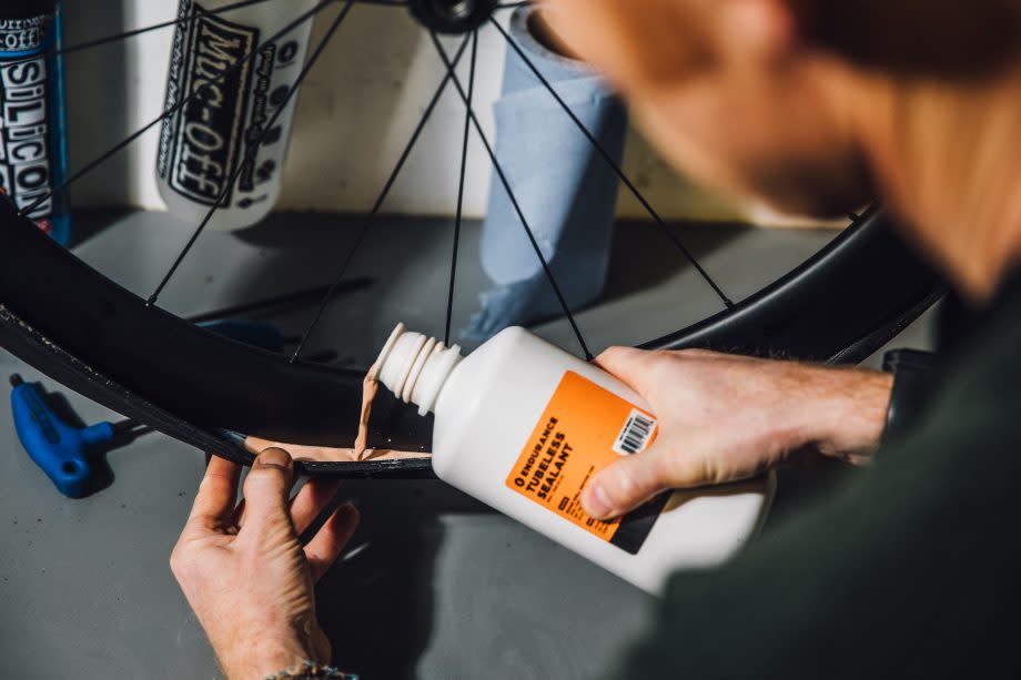 Male cyclist adding tubeless sealant to a tubeless tire