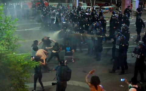 Police use tear gas to break up protesters gathered outside of the Phoenix - Credit: AFP