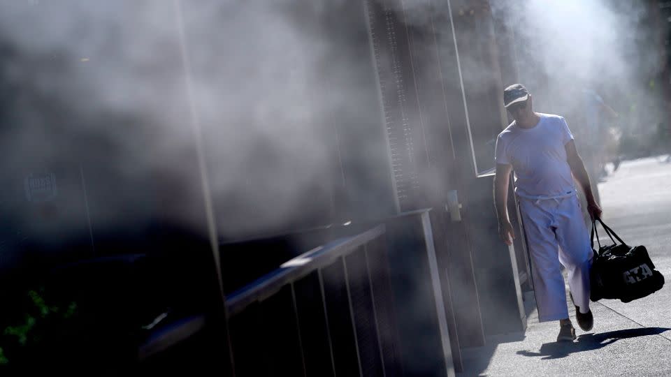 A man cools off under misters in Phoenix on Friday, where temperatures continued to top 110 degrees.  - Matt York/AP