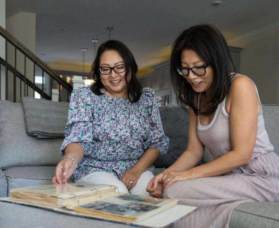 Becca Webster, left, and her sister, Dee Iraca, look at childhood photos in Davidson in May 2023. Khadejeh Nikouyeh/Knikouyeh@charlotteobserver.com