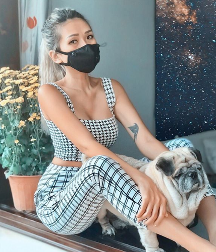 Jada Hai Phong Nguyen wearing a crop top and trousers and a black mask with her pug dog.