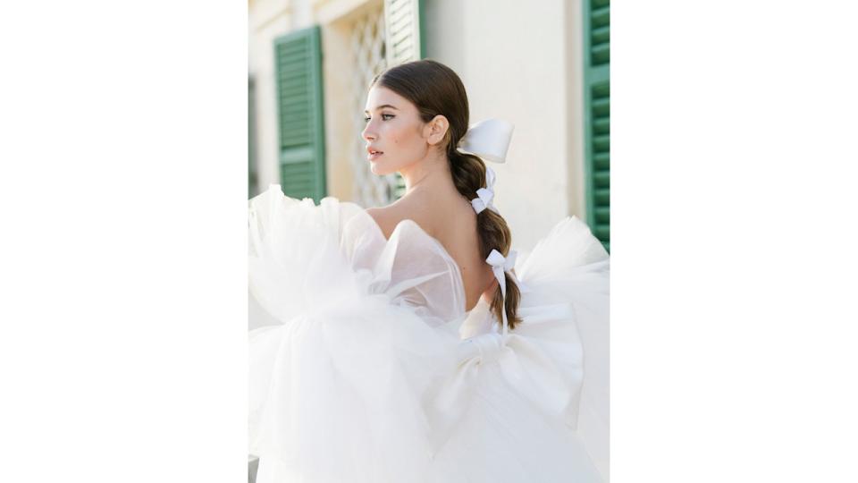 Woman with bubble braid and mesh dress gazes into distance 