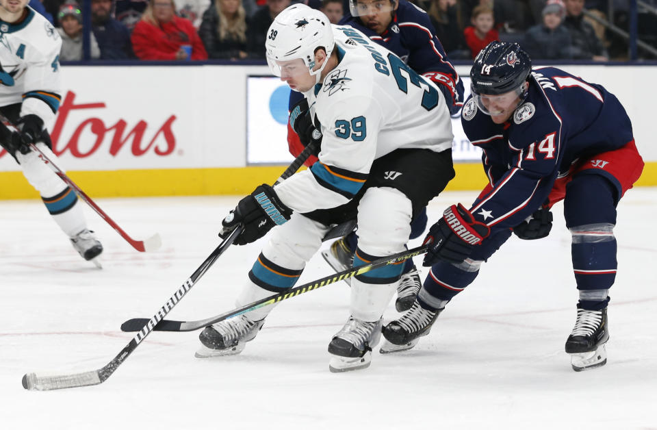 FILE - In this Jan. 4, 2020, file photo, San Jose Sharks' Logan Couture, left, skates the puck upice as Columbus Blue Jackets' Gustav Nyquist, of Sweden, defends during the third period of an NHL hockey game in Columbus, Ohio. The Sharks never managed to climb out of the deep hole they dug with a slow start last season. Avoiding the same fate this year is a high priority for the team, especially the condensed 56-game schedule and the extended road trip they are on to start this season. (AP Photo/Jay LaPrete, File)