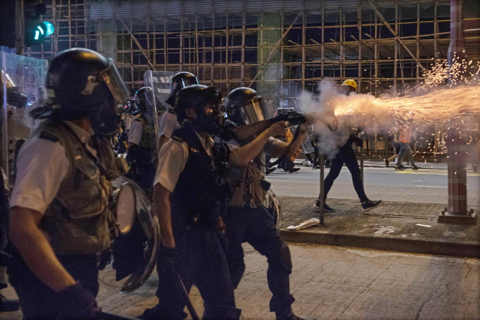Hong Kong police officers wear protective masks and fire tear gas at protesters in Sham Shui Po.