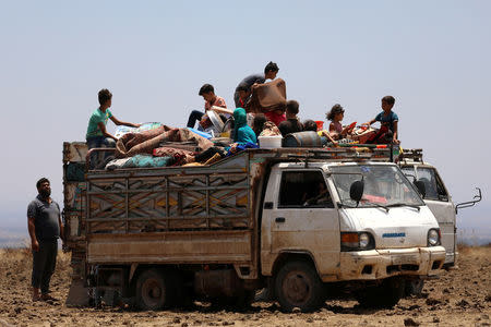 Internally displaced people from Deraa province sit on a truck loaded with belongings near the Israeli-occupied Golan Heights in Quneitra, Syria June 29, 2018. REUTERS/Alaa Al-Faqir