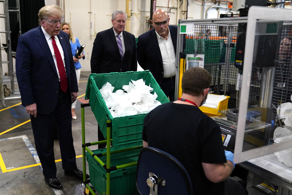 President Donald Trump watches masks being made as he participates in a tour of a Honeywell International plant that manufactures personal protective equipment, Tuesday, May 5, 2020, in Phoenix. Watching from left are White House press secretary Kayleigh McEnany, White House chief of staff Mark Meadows and Tony Stallings, vice president of integrated supply chain at Honeywell International Inc. (AP Photo/Evan Vucci)