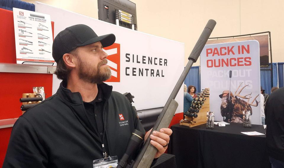 Mike Bleil of Silencer Central looks at a sound suppressor on the end of a deer hunting rifle Friday at the USA International Sportsmen's Show and Outdoor Recreation & Travel Show in Monroeville.
