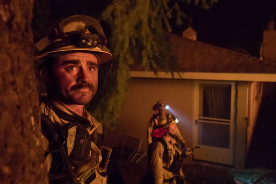 <p>A firefighter looks at a hillside ablaze after lighting a backfire, saving a home in Kenwood on Tuesday, Oct. 10, 2017. (Photo: Paul Kuroda via ZUMA Wire) </p>