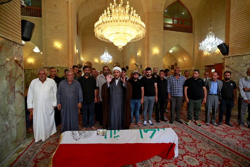 Mourners offer prayers next to the coffin of a demonstrator who was killed at anti-government protests, during a funeral in a mosque in Najaf