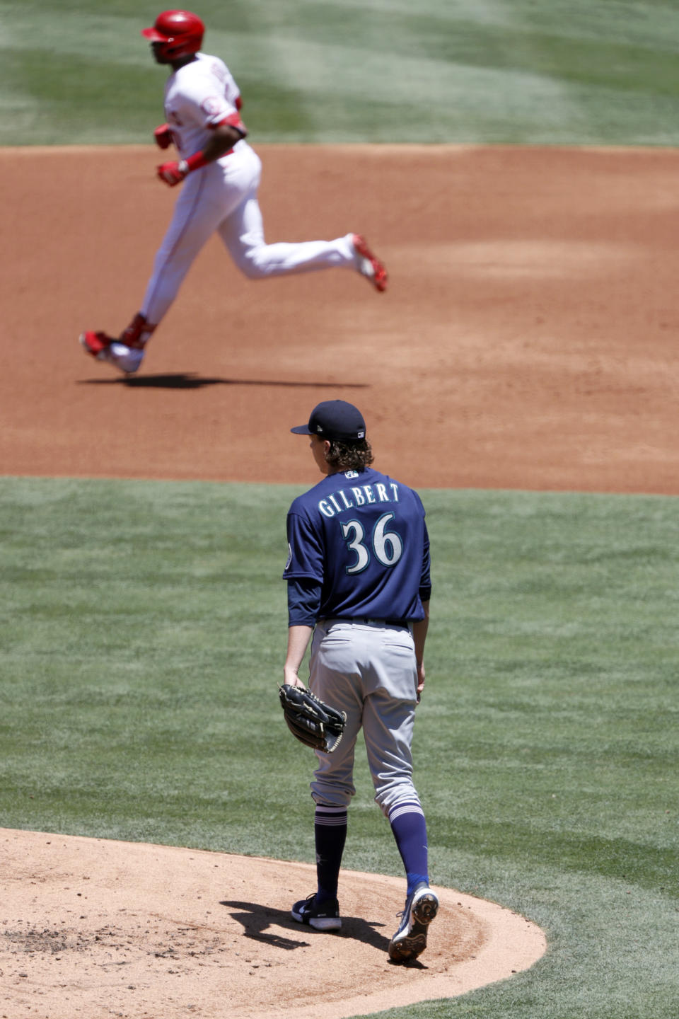 Seattle Mariners starting pitcher Logan Gilbert, bottom, looks on as Los Angeles Angels Justin Upton rounds the bases after hitting a solo home run during the first inning of a baseball game in Anaheim, Calif., Sunday, June 6, 2021. (AP Photo/Alex Gallardo)