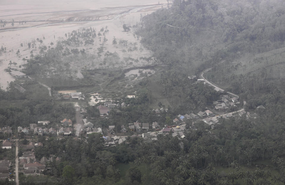 A village is covered by ash from the eruption of Mount Semeru in Lumajang district, East Java province, Indonesia, Sunday, Dec. 5, 2021. The death toll from eruption of the highest volcano on Indonesia's most densely populated island of Java has risen with scores still missing, officials said Sunday as rain continued to pound the region and hamper the search.(AP Photo/Trisnadi)