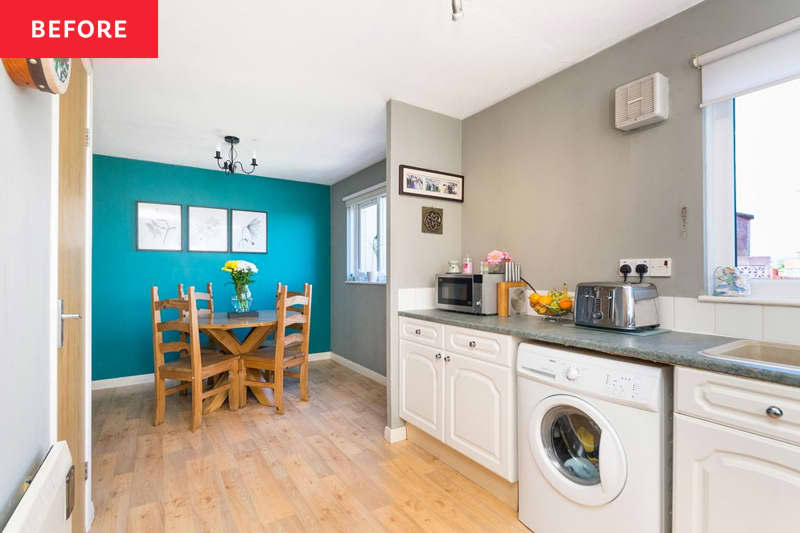 Wood dining table and chairs in turquoise room seen from gray kitchen with white cabinetry.