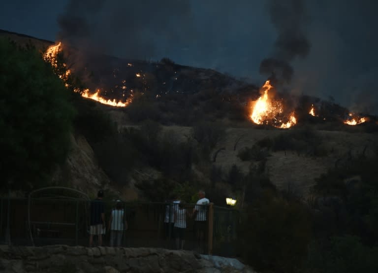 Residents stand in their yard as they watch an approaching fire at Fair Oaks Canyon in Santa Clarita, California